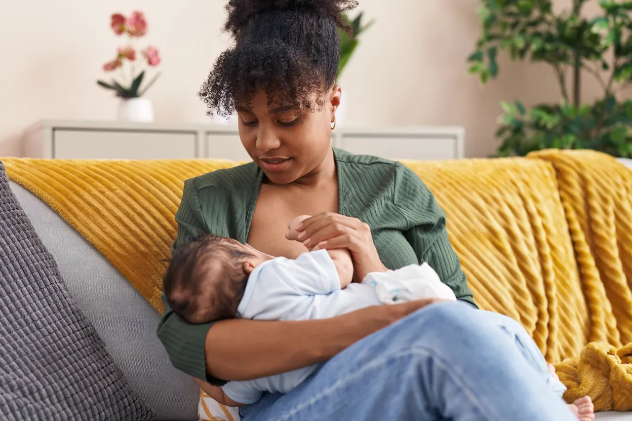 A mother breastfeeding her baby on a sofa at home